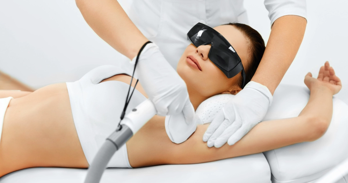 A woman wearing protective eyewear receiving laser hair removal in Greensboro, NC on her underarm from a professional in a clinical setting.